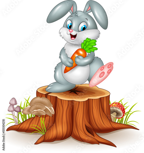 Little bunny holding carrot on tree stump