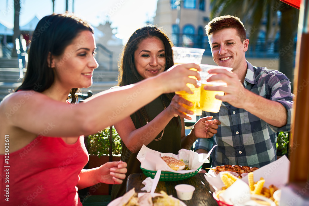 group of three friends making a toast with beer cups at lunch on summer day group of three friends making a toast with beer cups at lunch on summer day