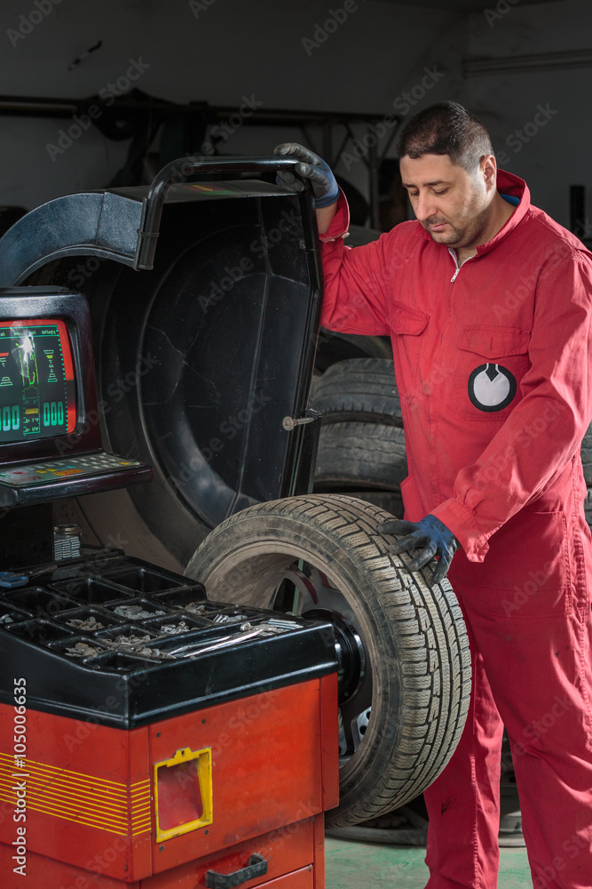 Mechanic balancing a tire on a balancing machine Mechanic balancing a tire on a balancing machine