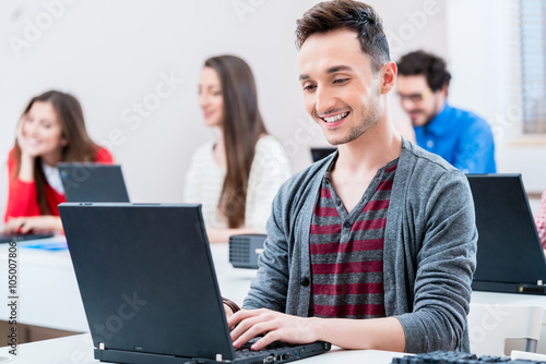 Student arbeitet am Laptop Computer in Hochschule  weitere Frauen und M  nner im Hintergrund