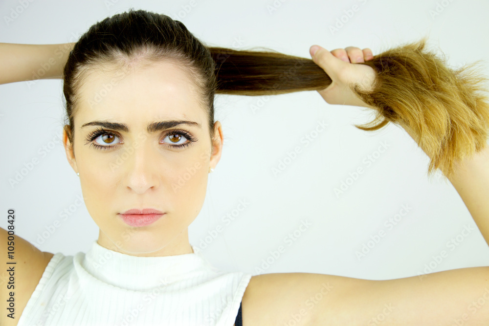 Beautiful female model pulling long hair in ponytail looking serious