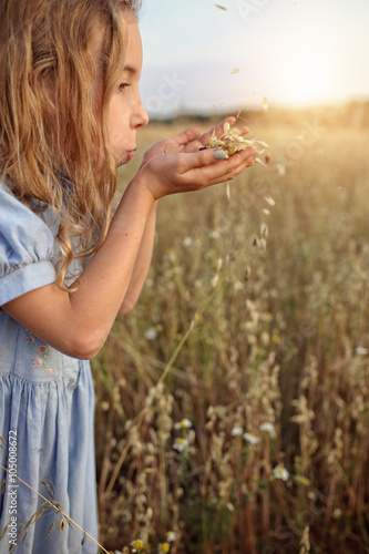 young girl inj the meadow blowing the seeds