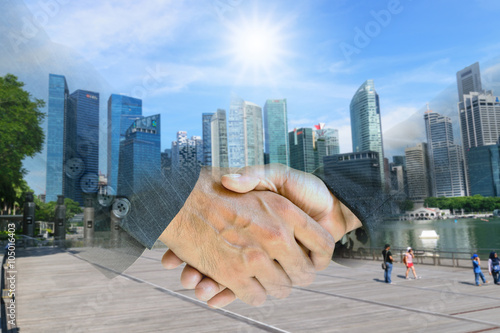 Double exporsure of business man and woman shaking hands with skyscraper.
