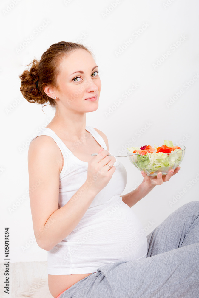 Beautiful young pregnant woman / teenager in white cloth eating healthy fresh salad with vegetebles Beautiful young pregnant woman / teenager in white cloth eating healthy fresh salad with vegetebles