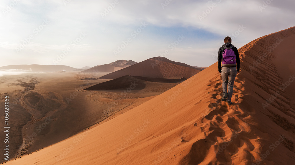 Solitary tourists up the crest of a dune in the desert of Namibia
