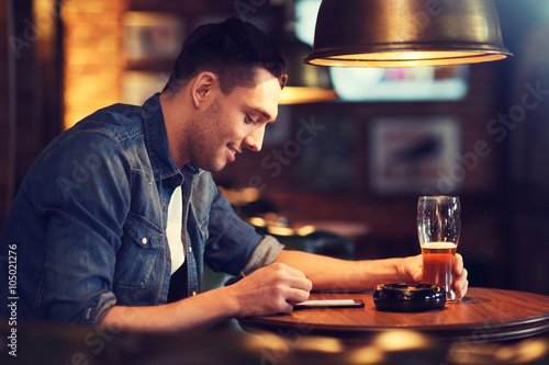 man with smartphone and beer texting at bar