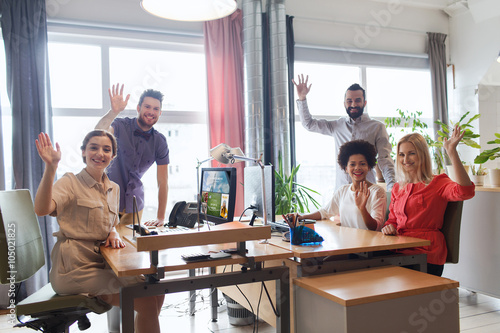 happy creative team waving hands in office