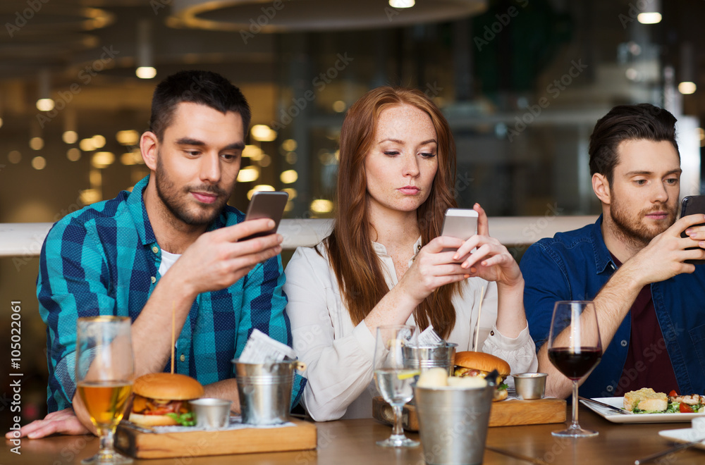 friends with smartphones dining at restaurant friends with smartphones dining at restaurant