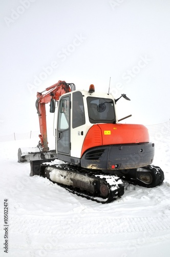 Tracklaying excavator at top of snow mountain