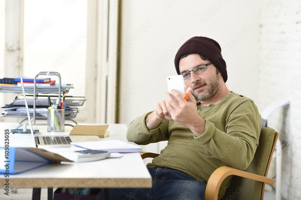 young attractive hipster businessman working from home office with mobile phone