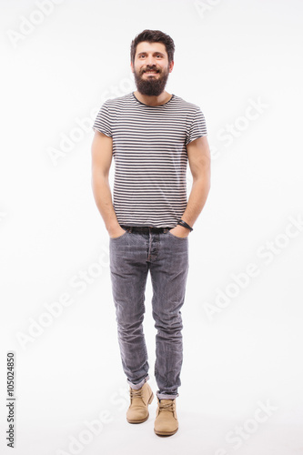 Handsome young man with beard full height walking while standing against white background