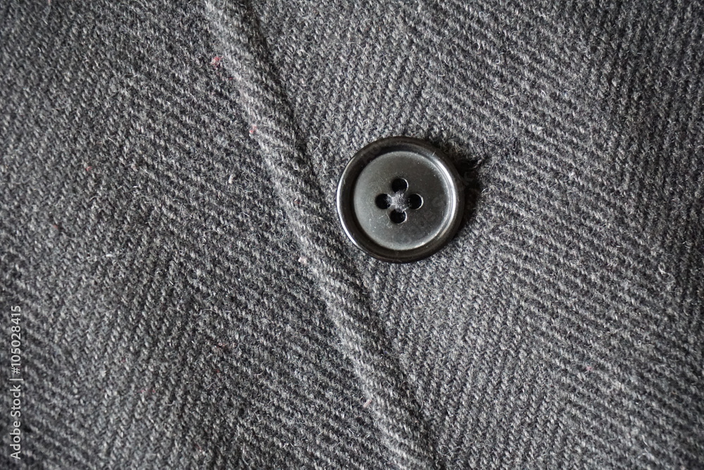 Detail of a dark button fastening the fish bone winter coat Detail of a dark button fastening the fish bone winter coat