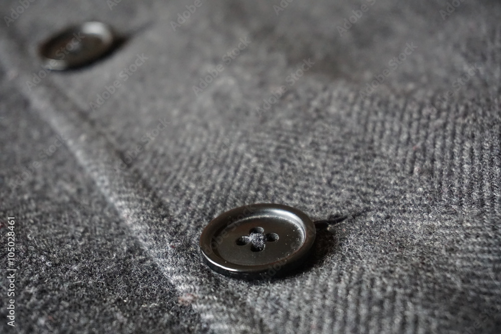 Detail of a dark button fastening the fish bone winter coat Detail of a dark button fastening the fish bone winter coat