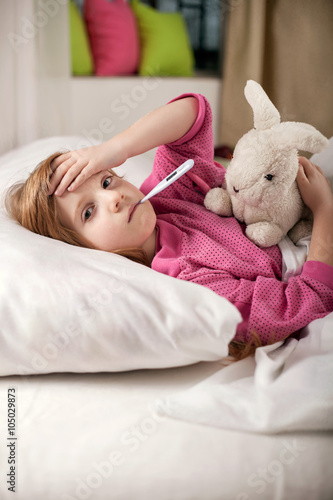 sick girl resting in bed with fever meassuring temperature with photo