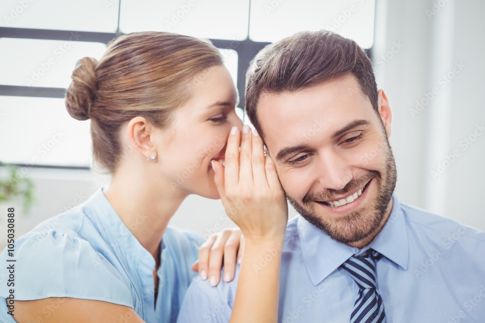 Happy businesswoman whispering to male colleague Happy businesswoman whispering to male colleague