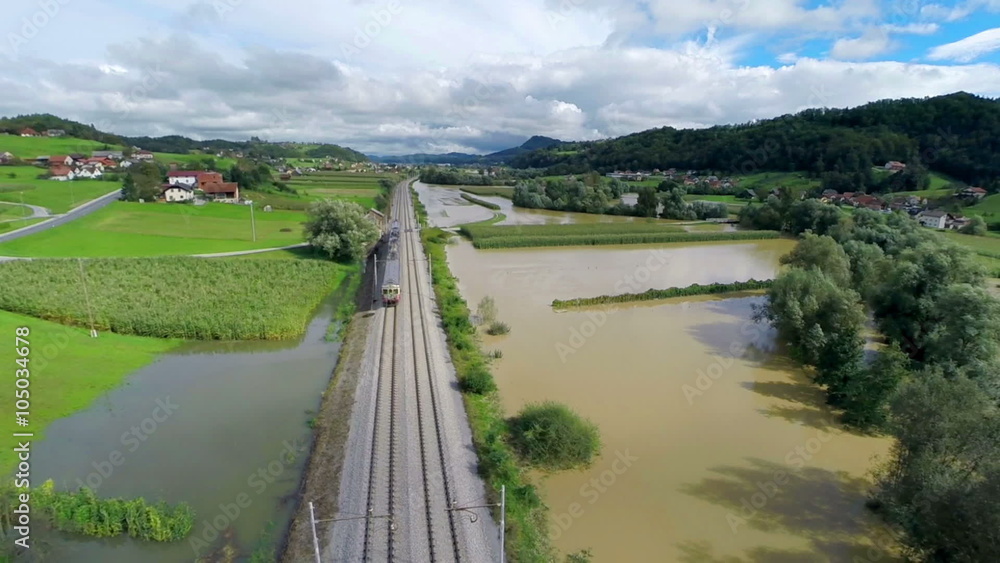 Flying over train tracks with train in flooded valley Flying over train tracks with train in flooded valley