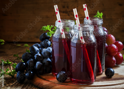 Tela Dark grape juice in glass bottles with straws, blue grapes, dark