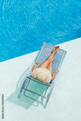 Fototapet woman enjoying on sunbed at swimming pool