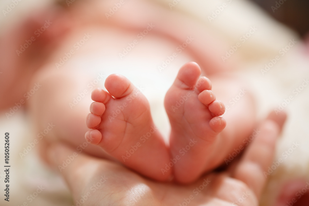 Mother holds in his hands a small baby foots Mother holds in his hands a small baby foots
