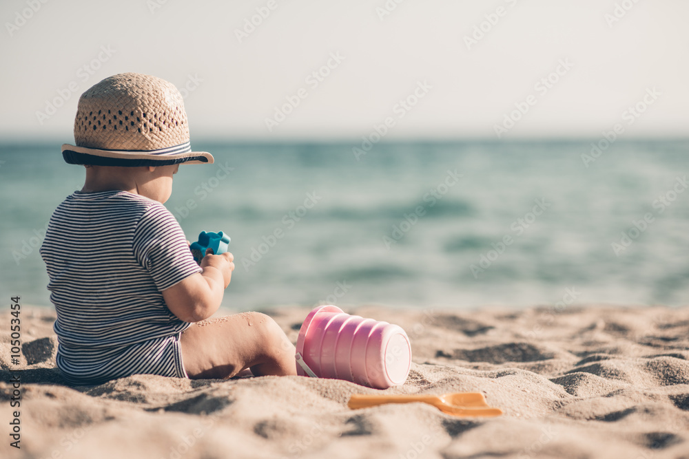 Cute baby boy playing with beach toys