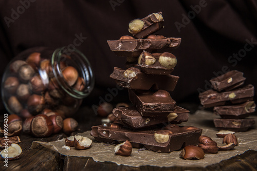 Fototapeta Naklejka Na Ścianę i Meble -  Плитки шоколада на бумаге с лесными орехами и банкой орехов