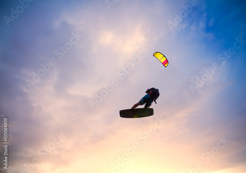 Kiteboarder performing a jump against sky at sunset