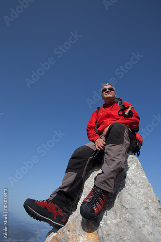 Hiker standing on top of the mountain with valley on the background.