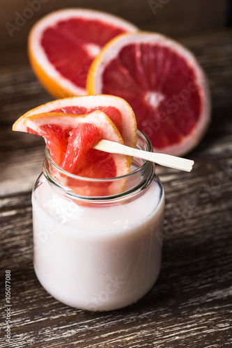 Delicious homemade organic yoghurt with grapefruit juice in a glass jar on wooden table
