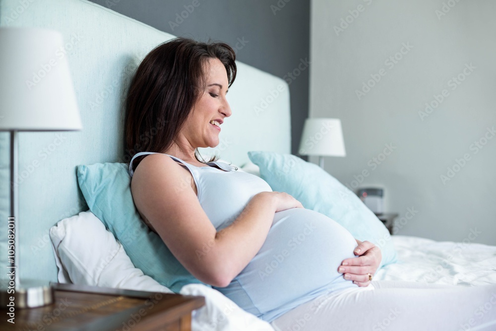 Pregnant woman lying in bed touching belly Pregnant woman lying in bed touching belly