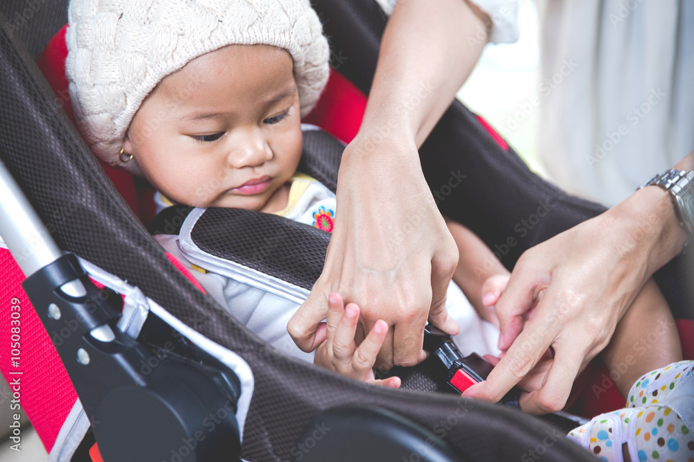 Mother securing her baby in the car seat in her car Mother securing her baby in the car seat in her car