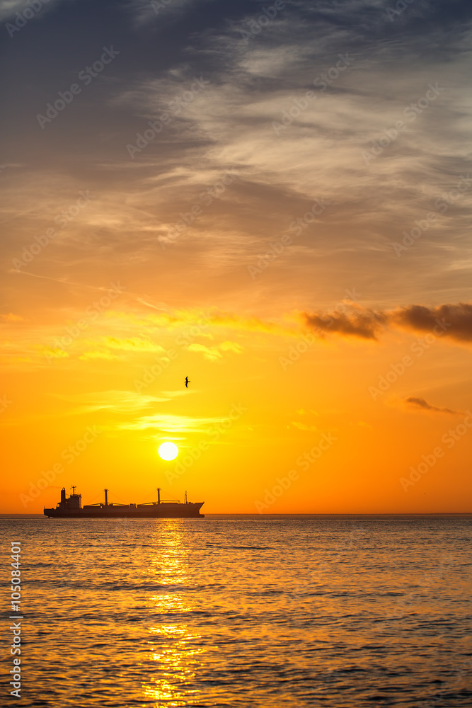 Cargo ship sailing on sunrise near the beach Cargo ship sailing on sunrise near the beach