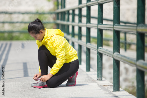 Young asian woman exercising outdoor in yellow neon jacket, tyin