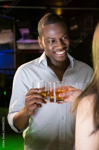 Man smiling while toasting his whisky glass in bar