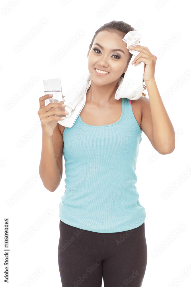 sporty woman wiping her sweat using towel while holding a glass sporty woman wiping her sweat using towel while holding a glass
