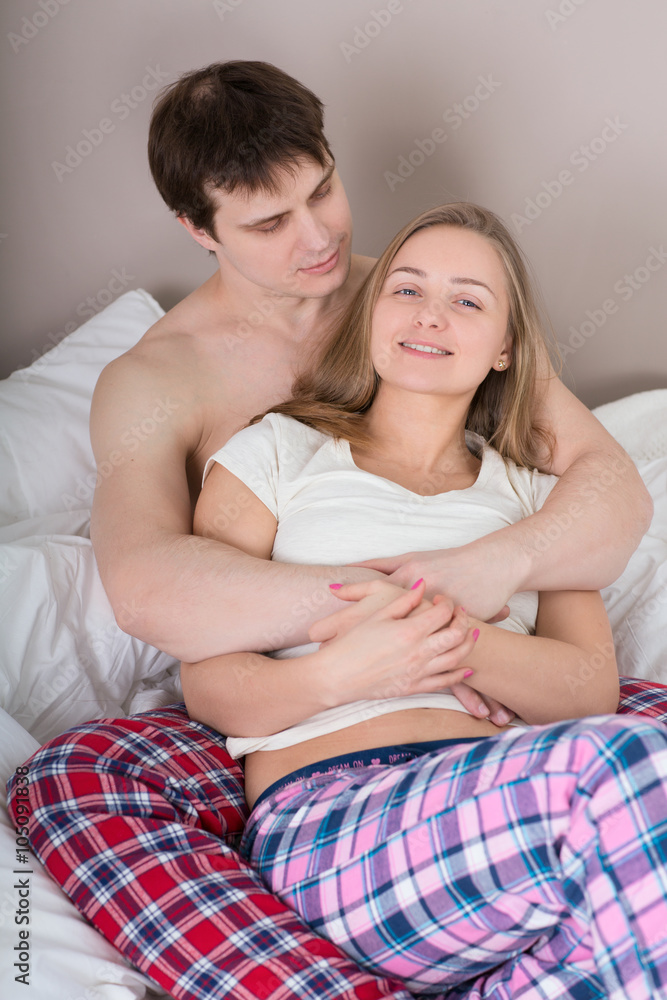 Happy young couple lying in bed and looking at camera with smiles
Happy young couple lying in bed and looking at camera with smiles