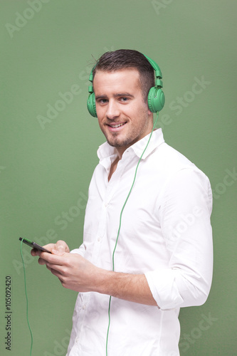 Handsome casual man listening to music with a smartphone on gree photo