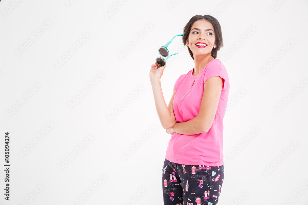 Smiling beautiful young woman standing and holding sunglasses Smiling beautiful young woman standing and holding sunglasses