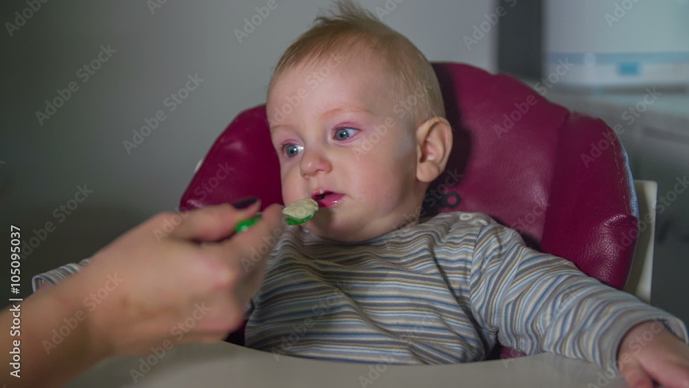 Mother feeds the little baby boy with spoon Mother feeds the little baby boy with spoon