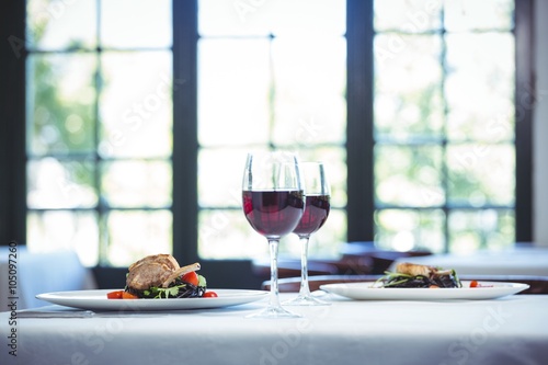 Tableau sur toile Squid ink spaghetti dish with basil for two with glasses of red wine in a restau
