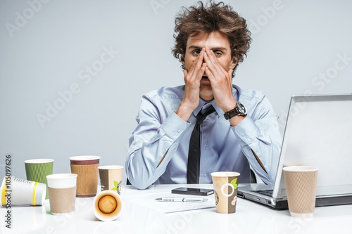 Exhausted man closed his eyes with his hands. Young student with lot of work, education concept