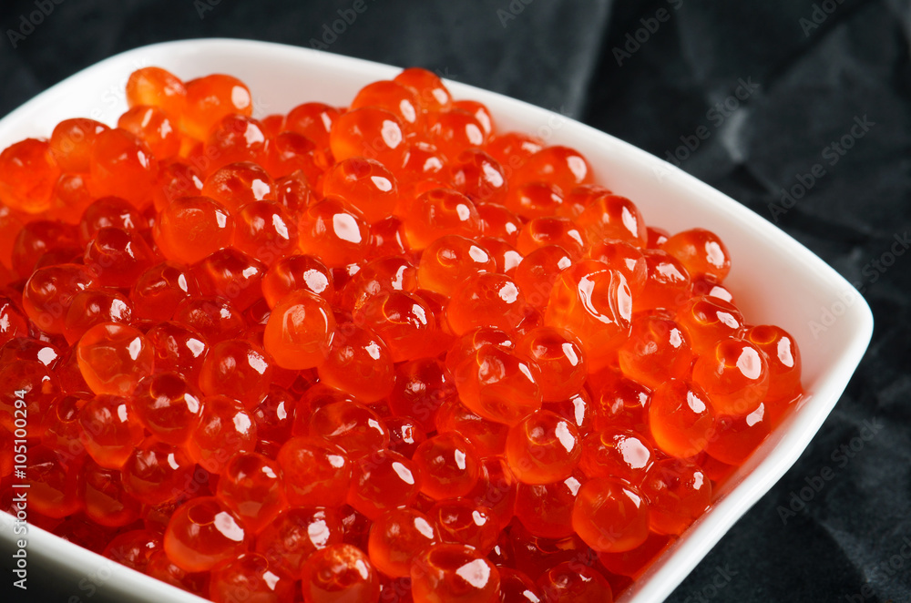 salmon caviar in the white ceramic bowl on the dark background salmon caviar in the white ceramic bowl on the dark background