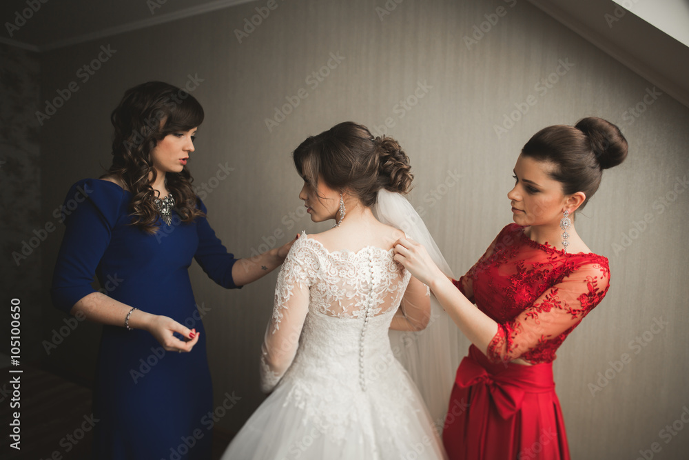 Happy buddies helps bride getting ready for her wedding day in the morning Happy buddies helps bride getting ready for her wedding day in the morning
