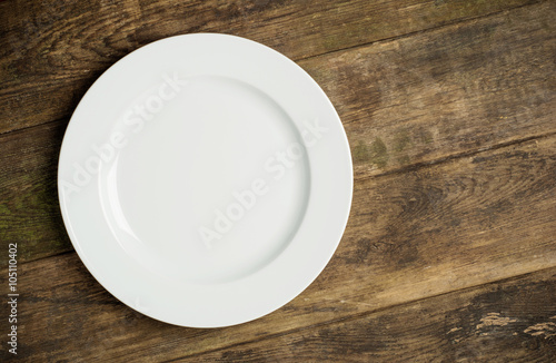 Empty white plate on rustic wooden background