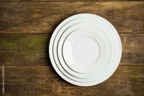 Empty white plates on rustic wooden background