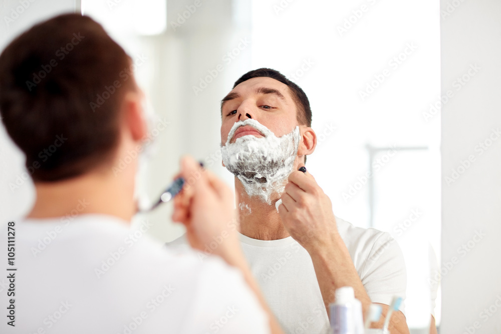man shaving beard with razor blade at bathroom