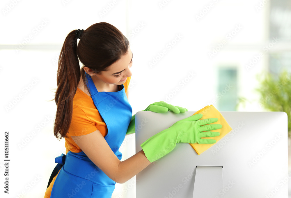 Young woman cleaning computer monitor at workplace in the office Young woman cleaning computer monitor at workplace in the office