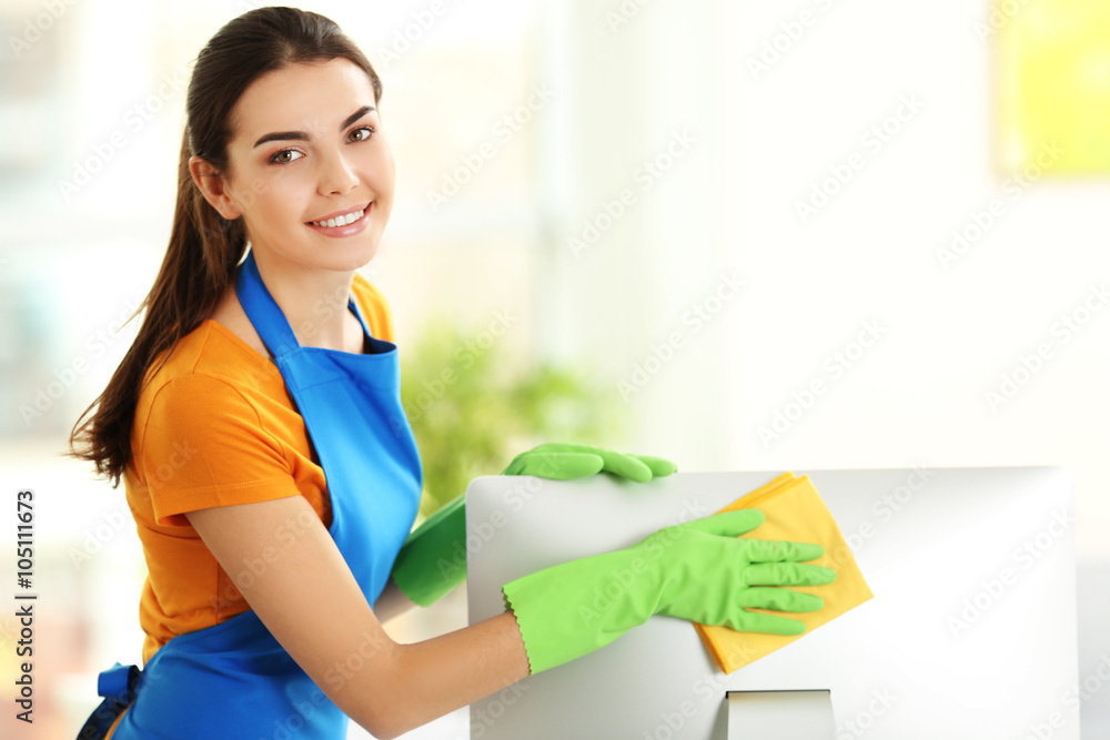Young woman cleaning computer monitor at workplace in the office Young woman cleaning computer monitor at workplace in the office