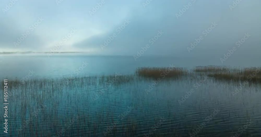 Time lapse of morning fog retreating and revealing a large lake and clear skies
