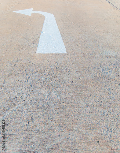 Close-up of cement street floor with white painted arrow sign