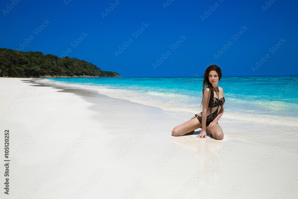 Sexy beautiful girl with long hair in black bikini relaxing on e